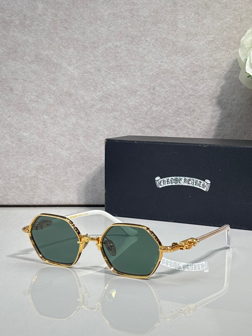 Round sunglasses with gold frames and green-tinted lenses, ornate temple detailing