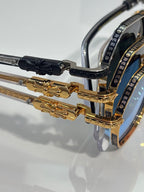 Sunglasses temple hinge in gold and black with ornate metal accents and lens rim