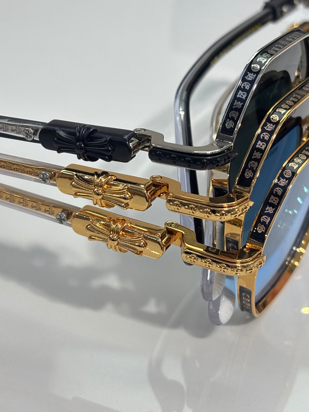 Sunglasses temple hinge in gold and black with ornate metal accents and lens rim