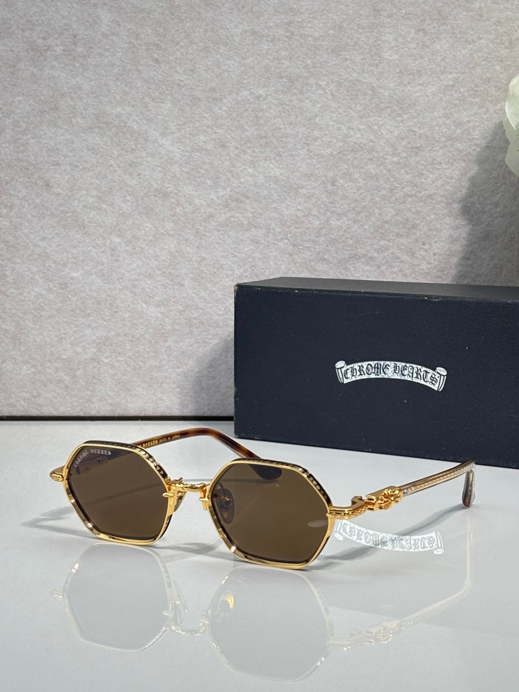 Round sunglasses with gold frames and brown-tinted lenses, ornate temple detailing
