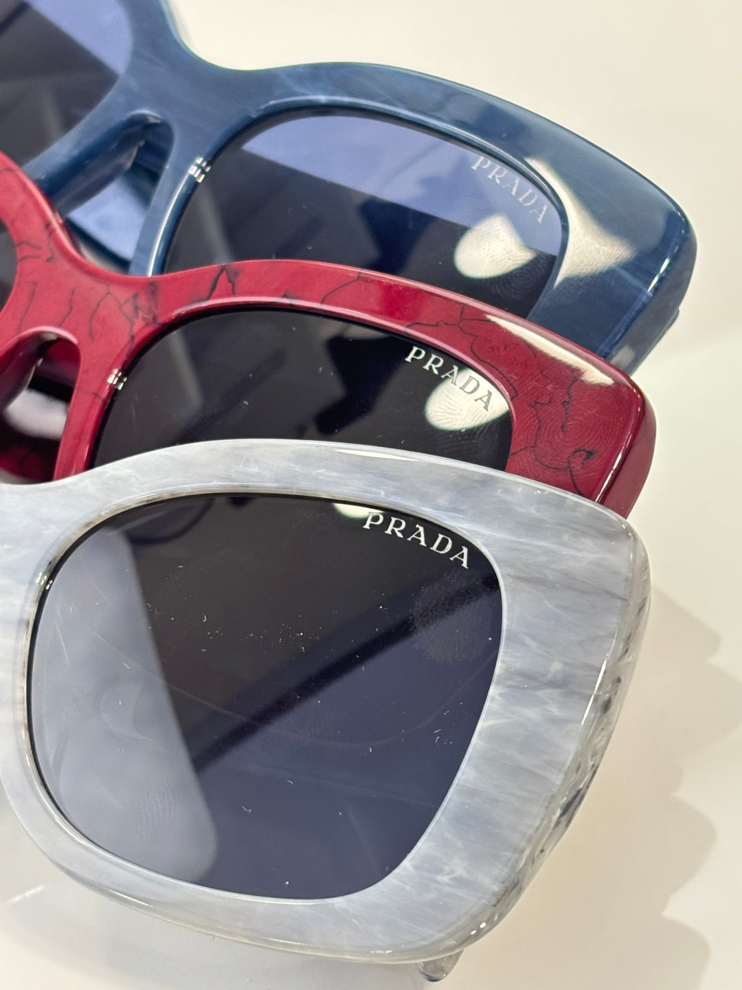 Prada square sunglasses close-up with blue, red, and clear silver frames
