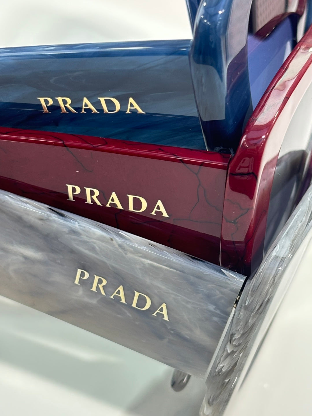Prada sunglasses cases with PRADA lettering in red, blue, and silver