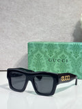 Gucci sunglasses with dark navy square frames and dark lenses, gold Gucci logo on temple
