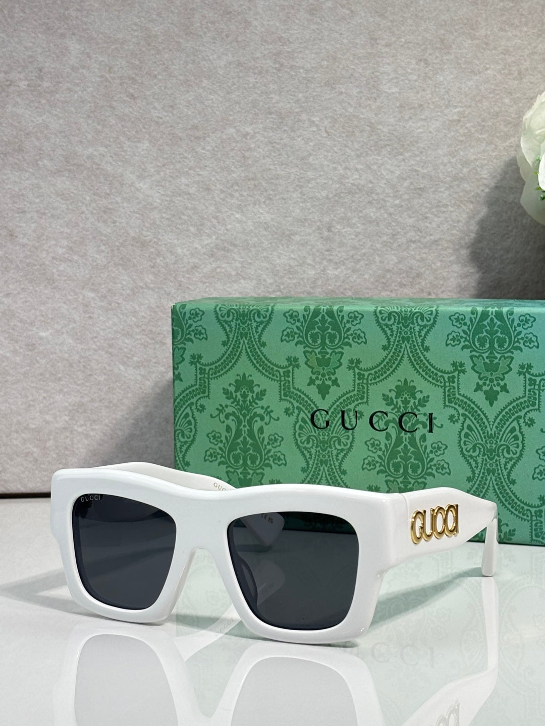 Gucci sunglasses with white square frames and dark lenses, gold Gucci logo on temple