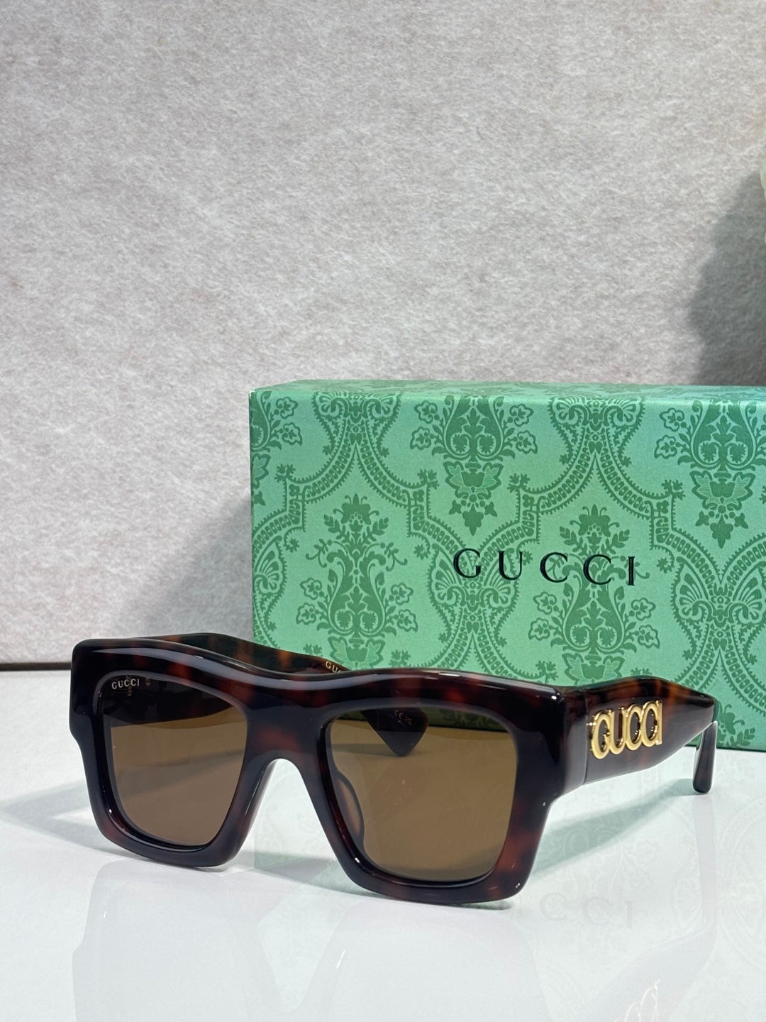 Gucci sunglasses with tortoiseshell square frames and amber lenses, gold Gucci logo on temple