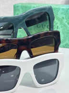 Gucci sunglasses pair with dark green and tortoiseshell frames, white lenses and gold Gucci logo