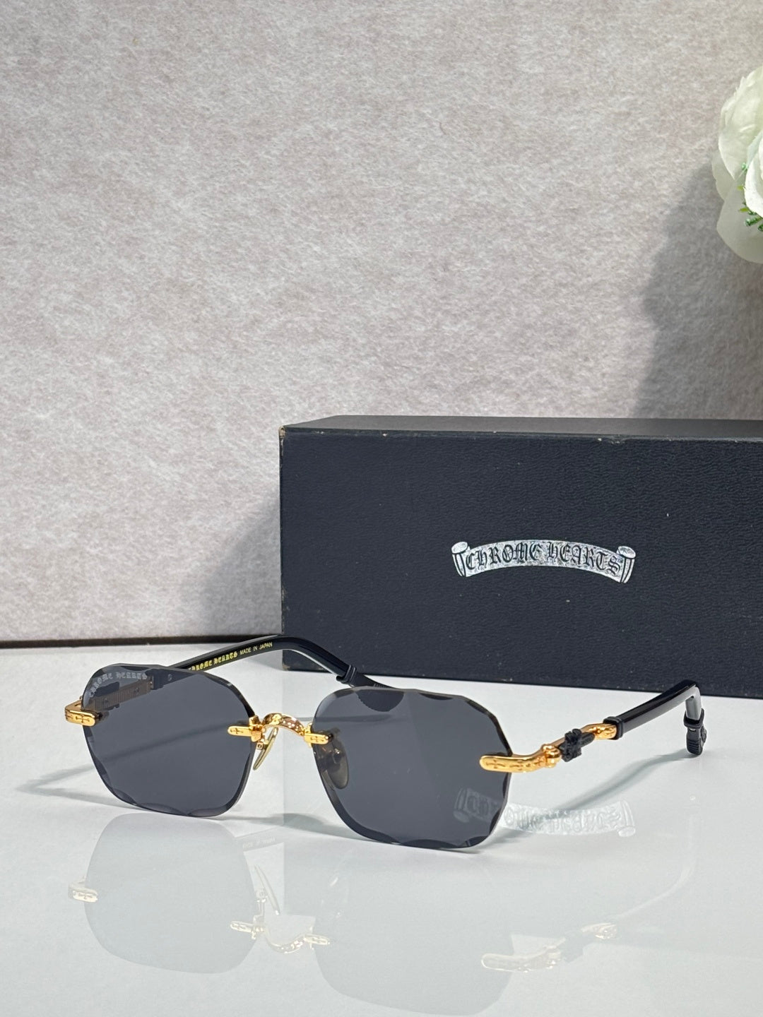 Chrome glasses with dark lenses, gold details, and black temple arms on display
