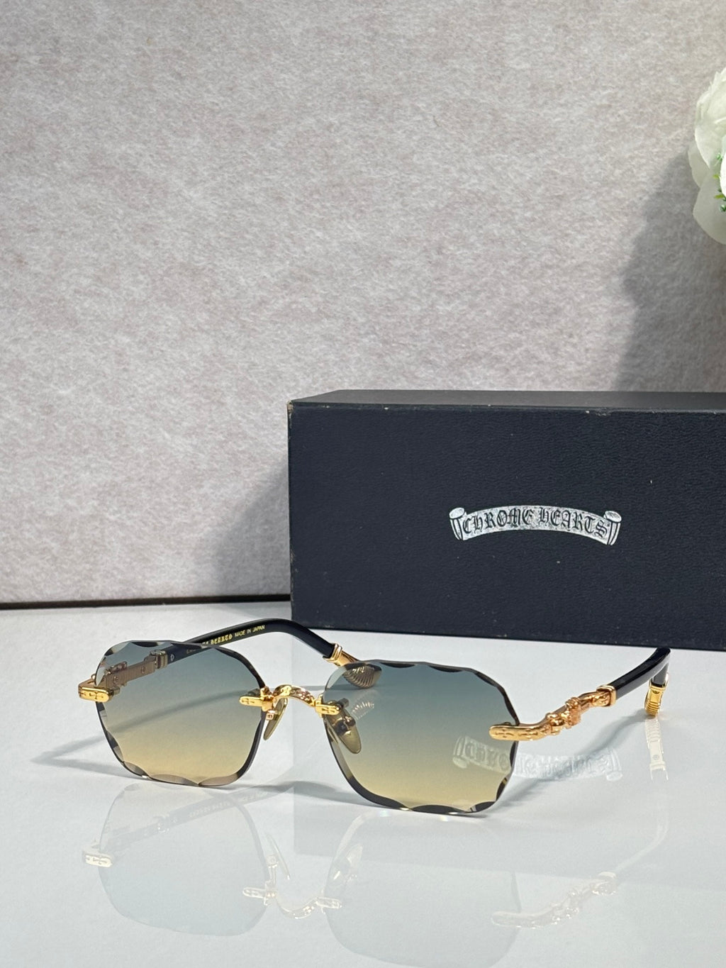 Chrome glasses with blue tinted lenses, gold accents, and patterned black temple arms
