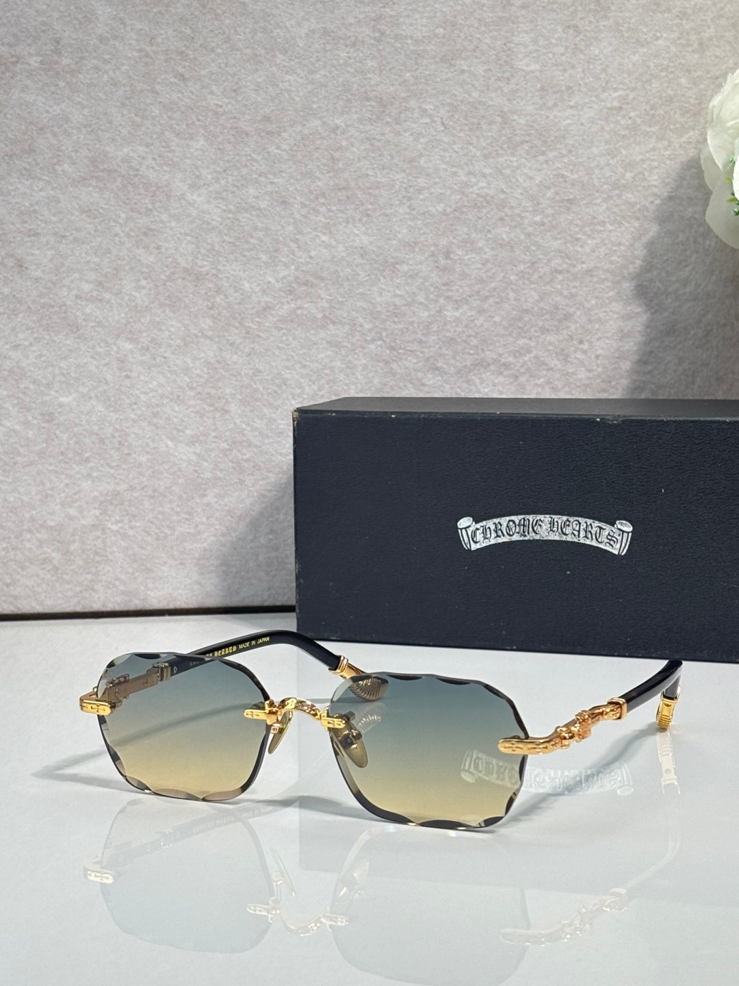 Chrome glasses with blue tinted lenses, gold accents, and patterned black temple arms