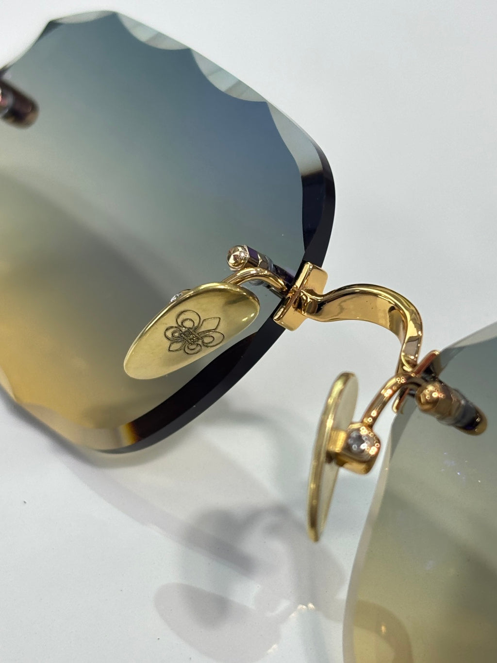 Chrome glasses close-up: gold temple hinge and arm detail on blue-tinted lens