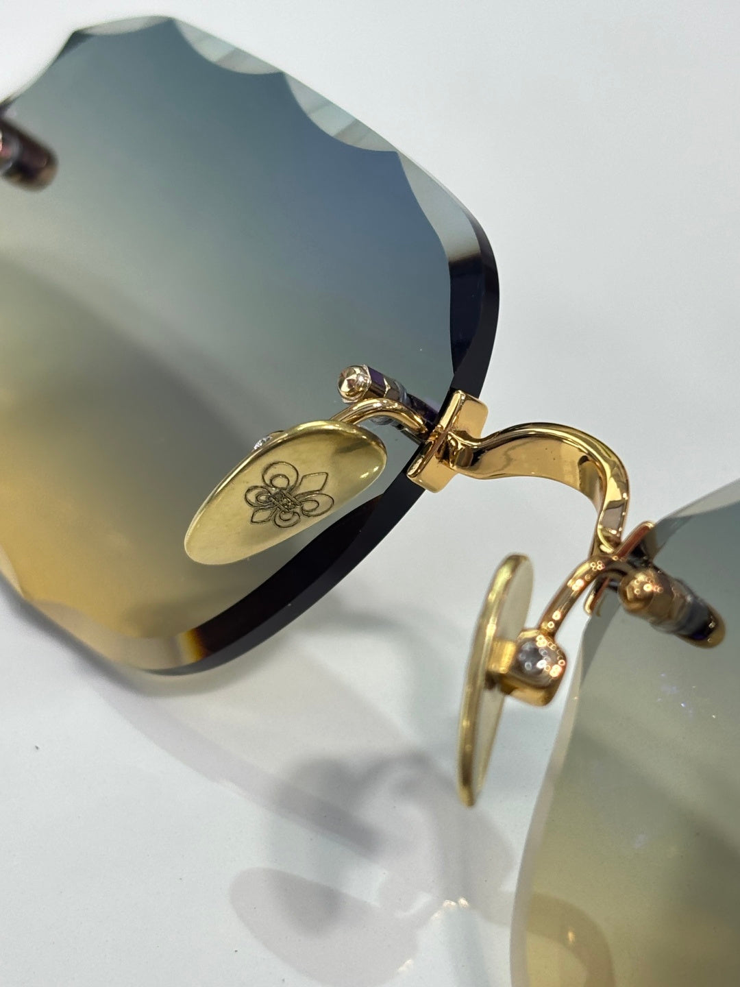 Chrome glasses close-up: gold temple hinge and arm detail on blue-tinted lens