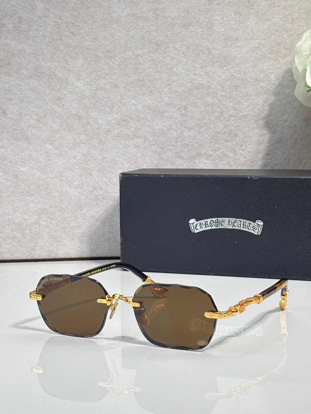 Chrome glasses with brown tinted lenses, gold frame details, and patterned temples