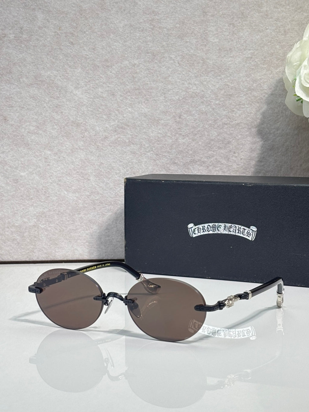 Round eyeglasses with dark lenses and silver-tone frame, with case behind