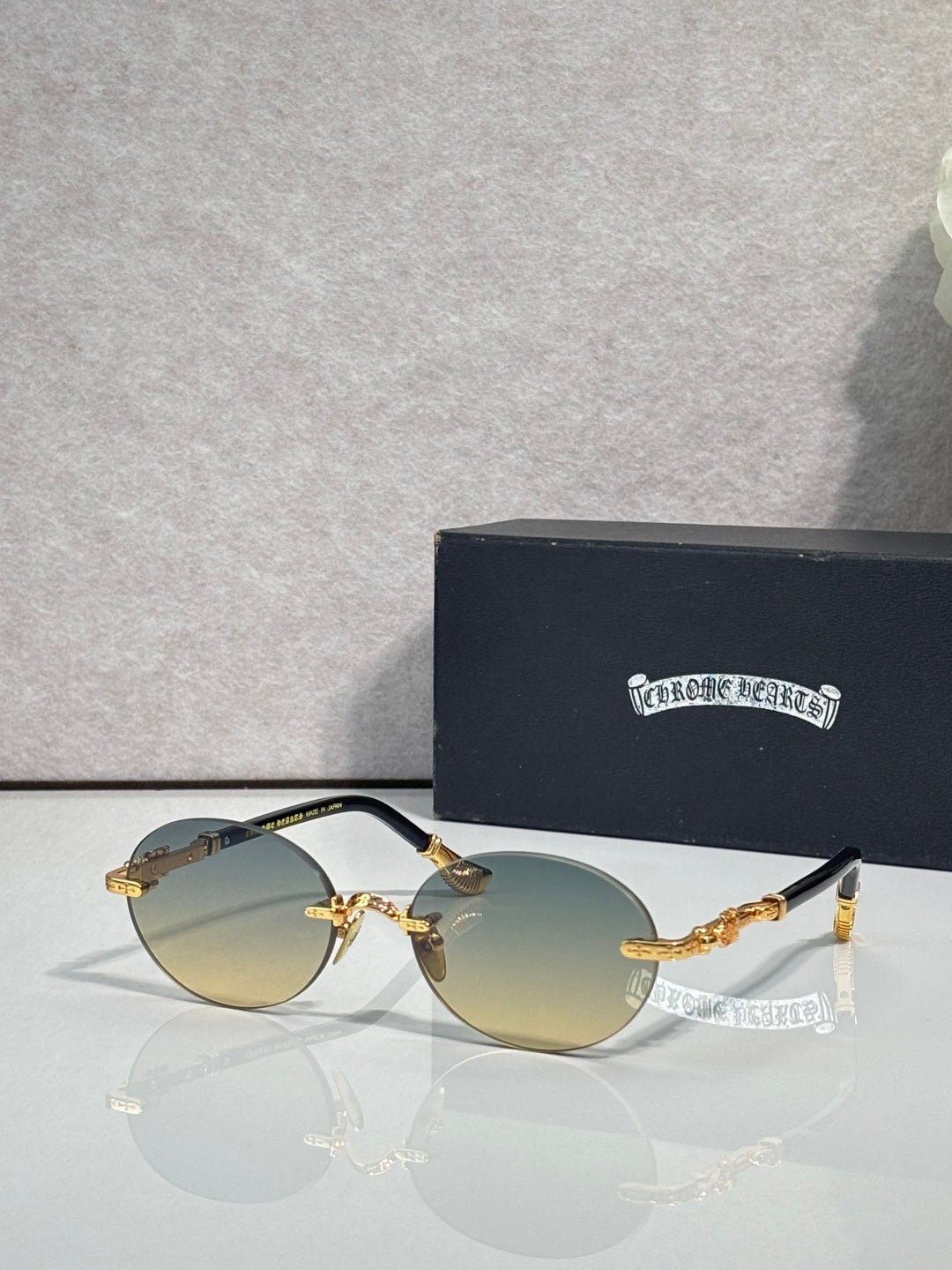 Round eyeglasses with gold-tone frame and light amber lenses, shown with case