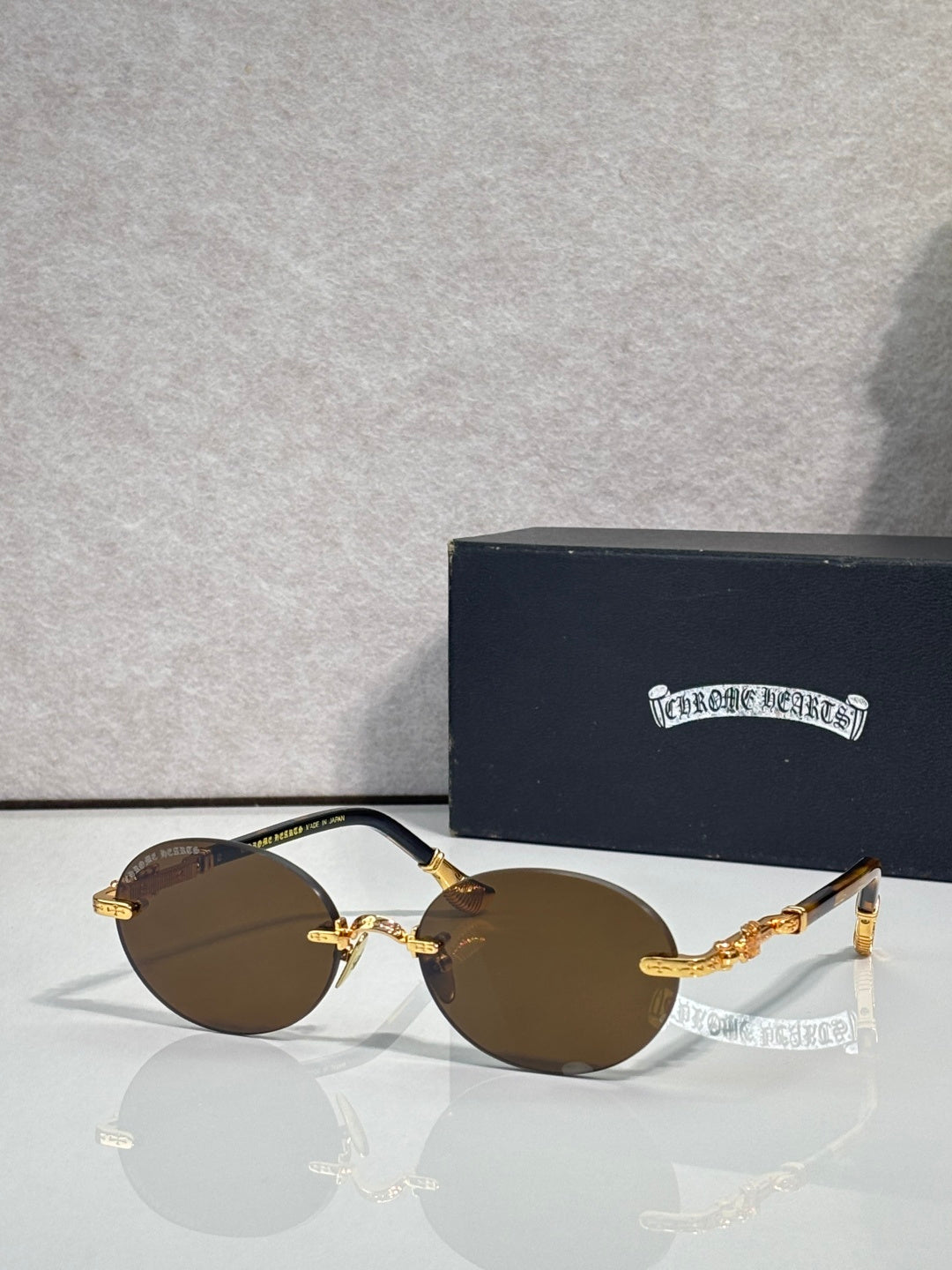 Round eyeglasses with gold-tone frame and dark lenses, with protective case