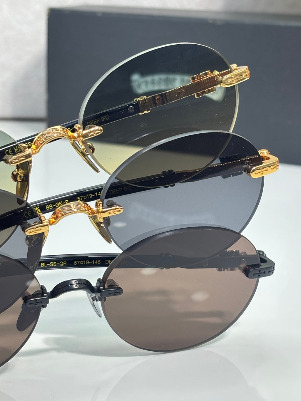 Stacked round eyeglasses with gold-tone frames and tinted lenses, with case behind