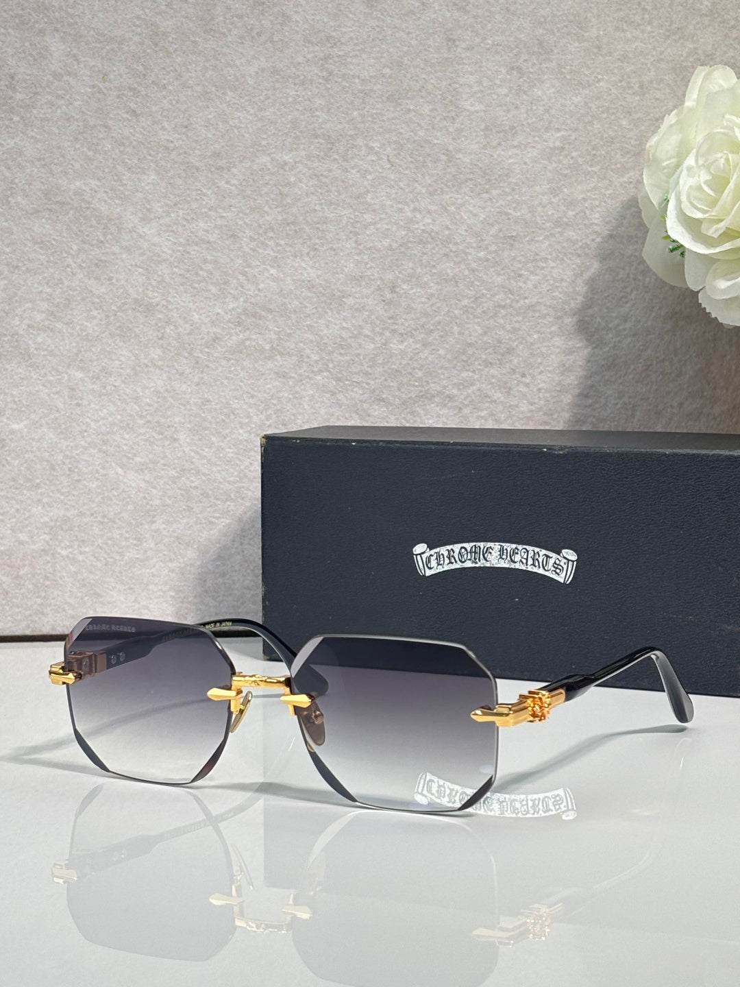 Chrome glasses with dark gray lenses, black frame, gold-tone arms and hinges