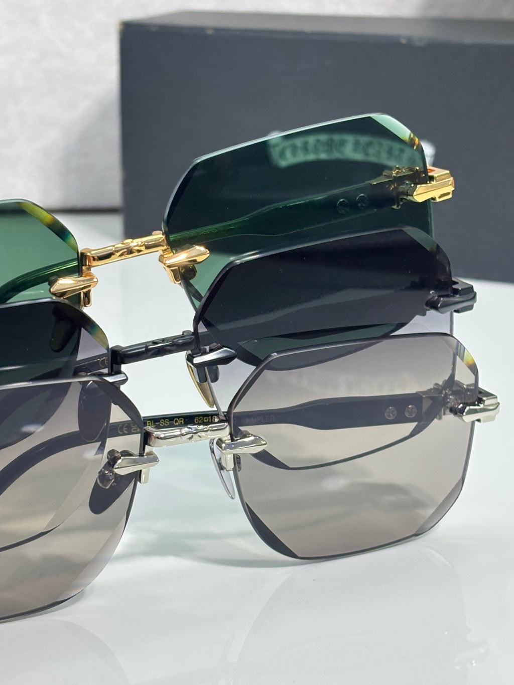 Chrome glasses with green-tinted lenses and black frame, gold arms and hinge detail