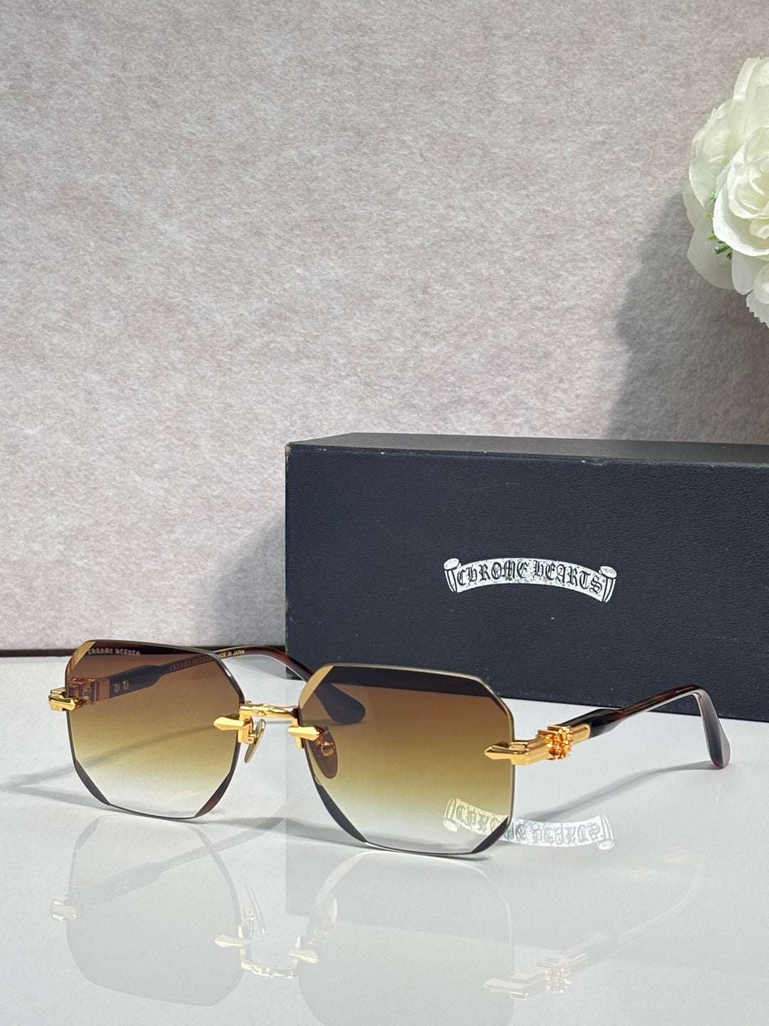 Chrome glasses with amber-tinted lenses, black frame, gold-tone arms with logo