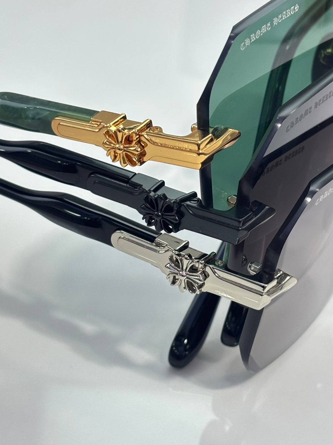 Chrome glasses close-up: gold and black hinge details with lens and arm logo