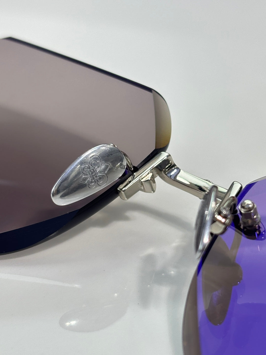 Chrome glasses close-up: silver temple hinge and purple-tinted lens edge