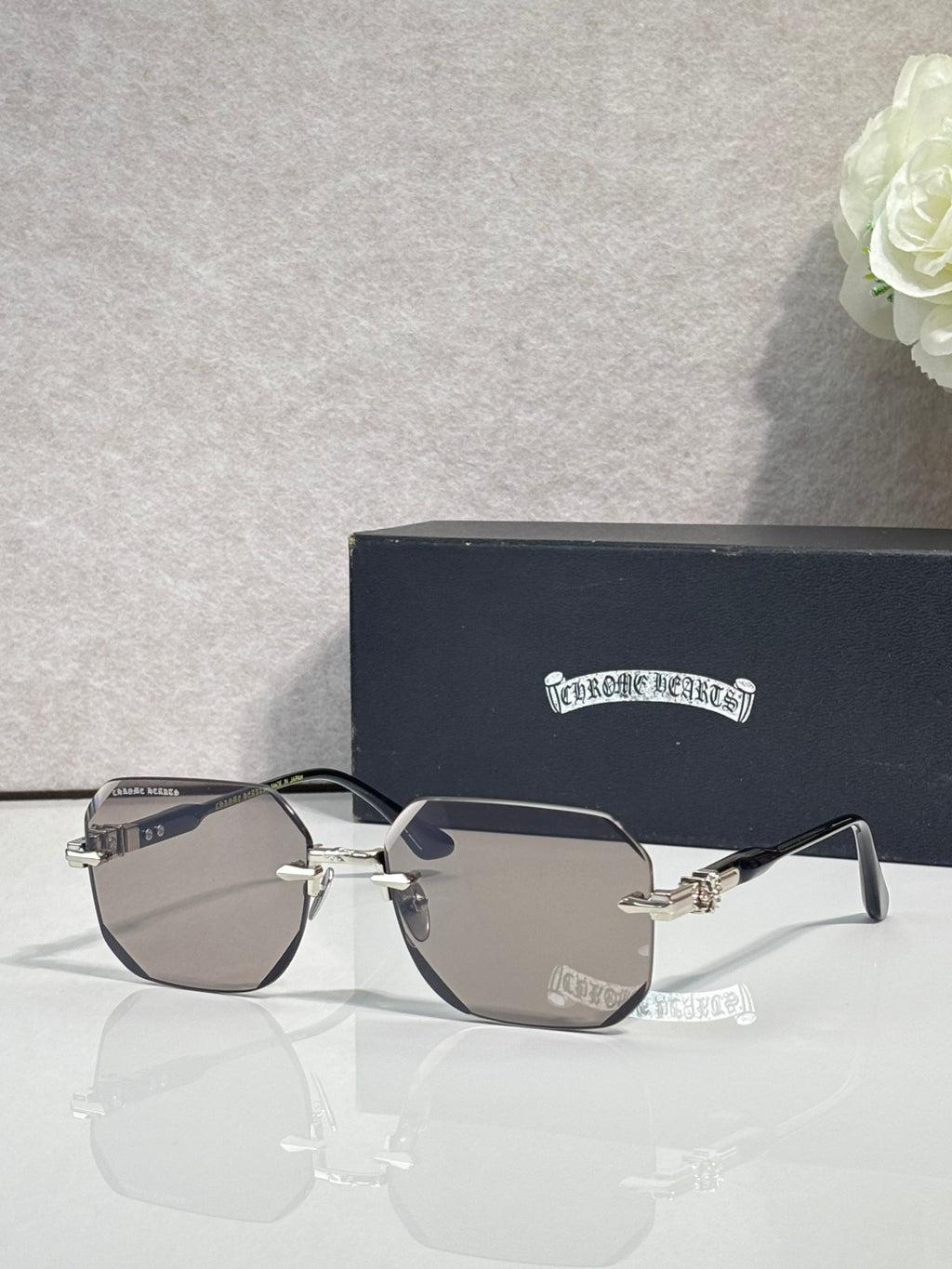 Chrome glasses with gray lenses, black frame, chrome arms with ornate logo detail