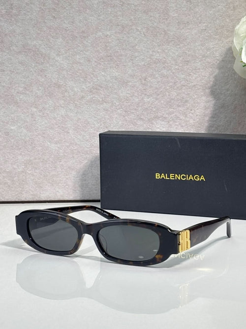 Balenciaga sunglasses with black frames and dark lenses, gold logo detail on temples