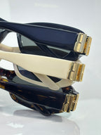 Balenciaga sunglasses close-up: gold temple hardware on cream and black frames