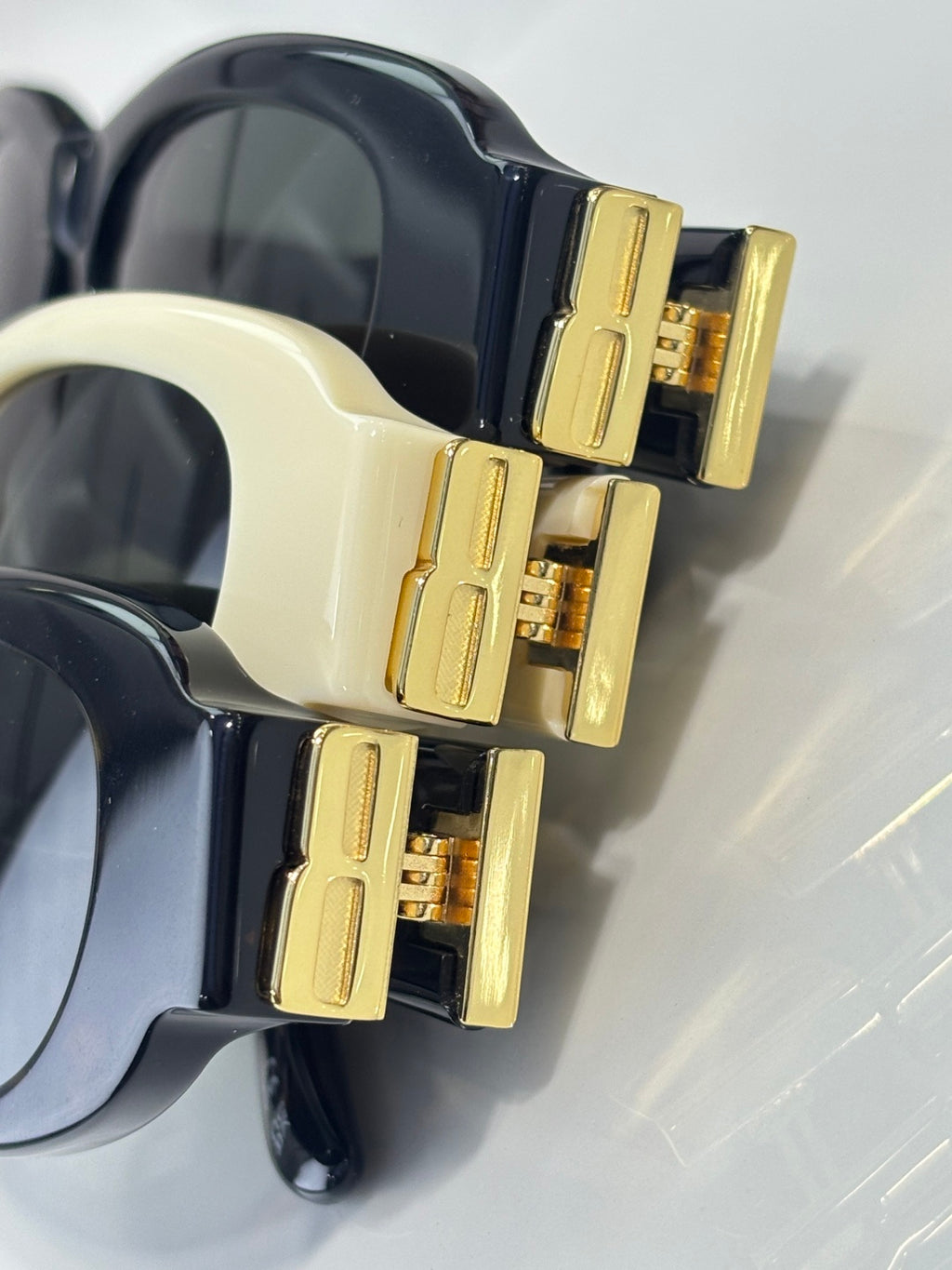 Balenciaga sunglasses close-up: gold temple details on black and cream oval frames