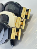 Balenciaga sunglasses close-up: gold temple details on black and cream oval frames