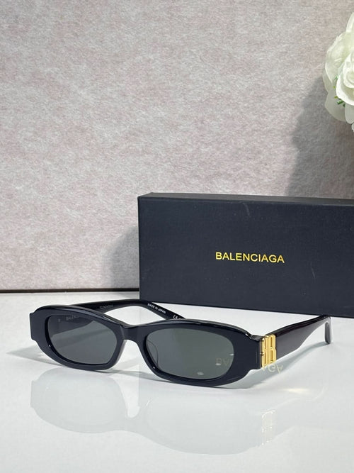 Balenciaga sunglasses with black oval frames and dark lenses, gold logo on side hardware