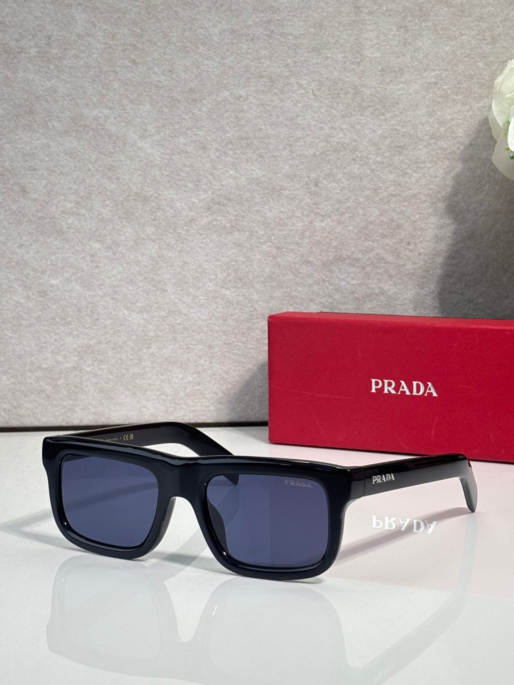 Prada sunglasses with dark blue rectangular frame and dark lenses, logo on arms.