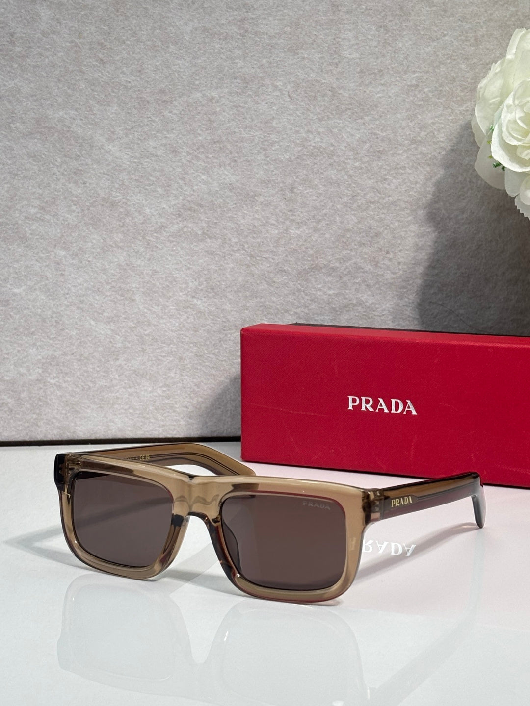 Prada sunglasses with tortoiseshell square frame and dark lenses, logo on arms.