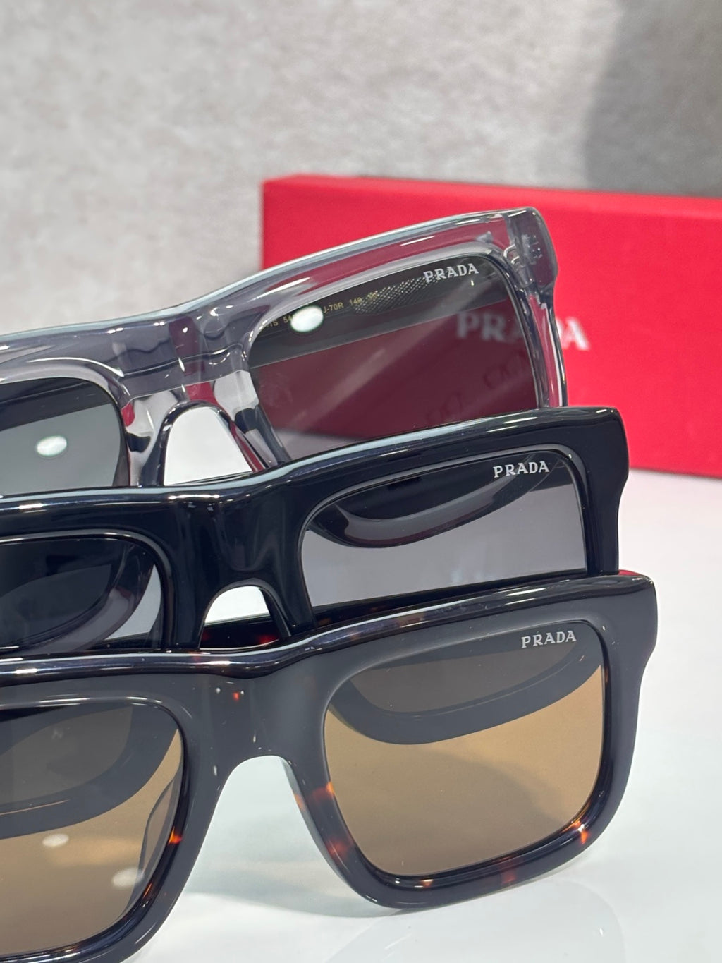 Prada sunglasses close-up with clear blue and dark frames, dark tinted lenses.