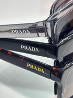 Prada sunglasses arm close-up with PRADA logo text and dark lens frame.