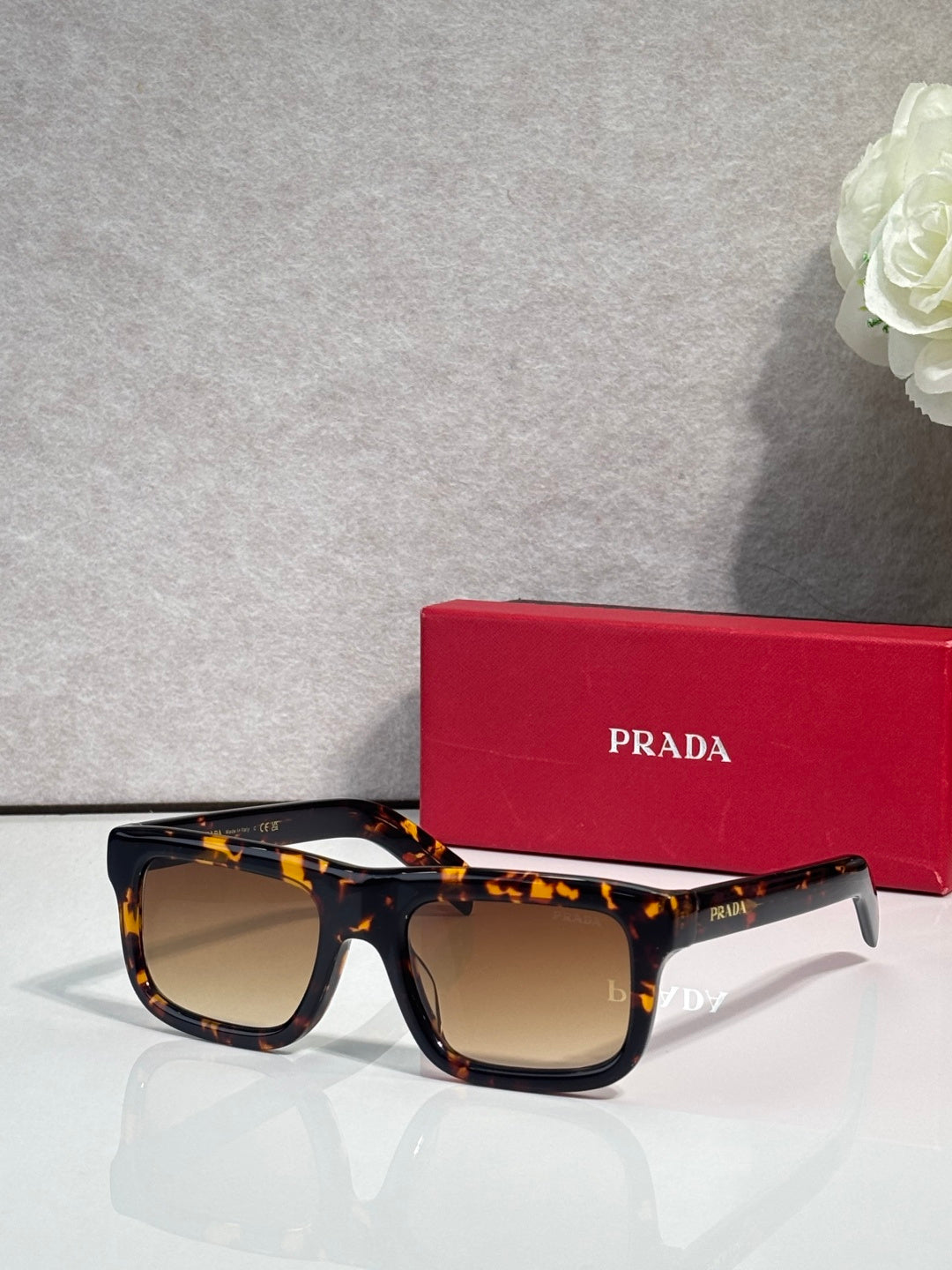 Prada sunglasses with tortoiseshell oversized square frame and dark lenses, logo on arms.