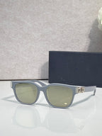 Dior sunglasses with muted blue frames, green tinted lenses, and gold logo hinge detail