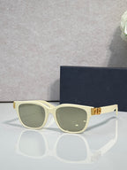Dior sunglasses with light green frames, olive tinted lenses, and gold logo hinge detail