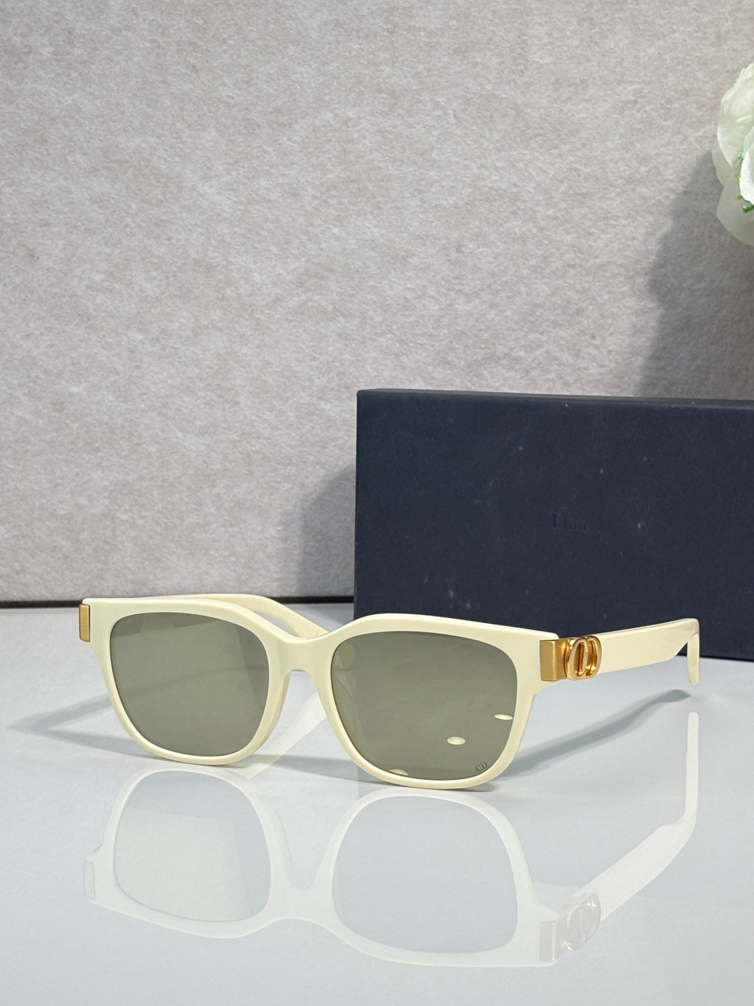 Dior sunglasses with light green frames, olive tinted lenses, and gold logo hinge detail