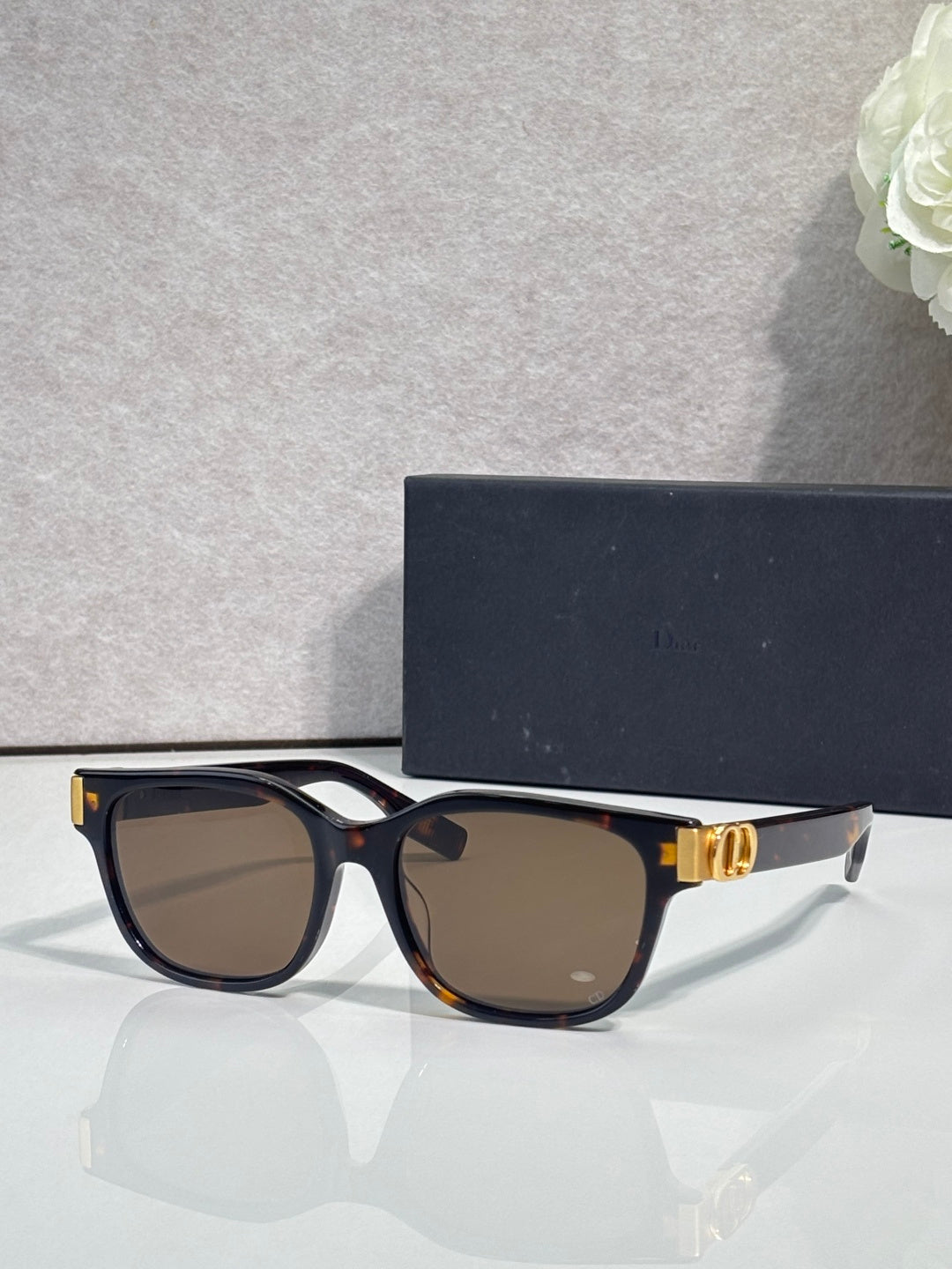 Dior sunglasses with dark frames, brown tinted lenses, and gold logo hinge detail