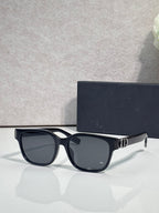 Dior sunglasses with dark frames, black tinted lenses, and gold logo hinge detail