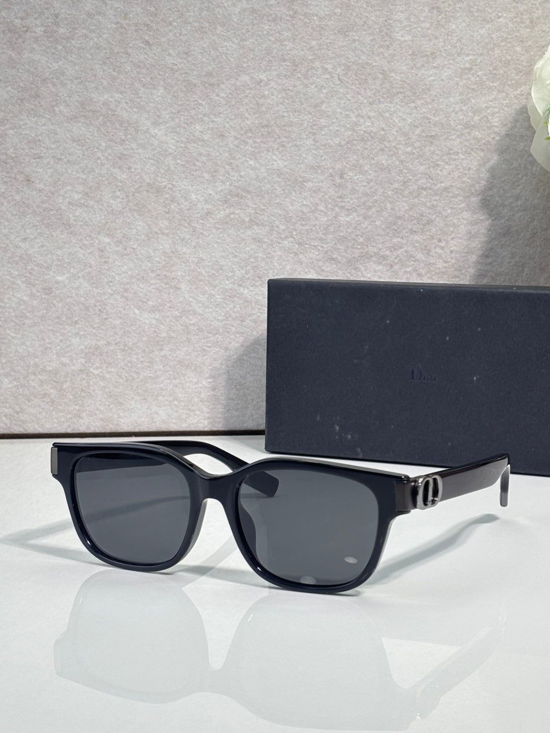 Dior sunglasses with dark frames, black tinted lenses, and gold logo hinge detail