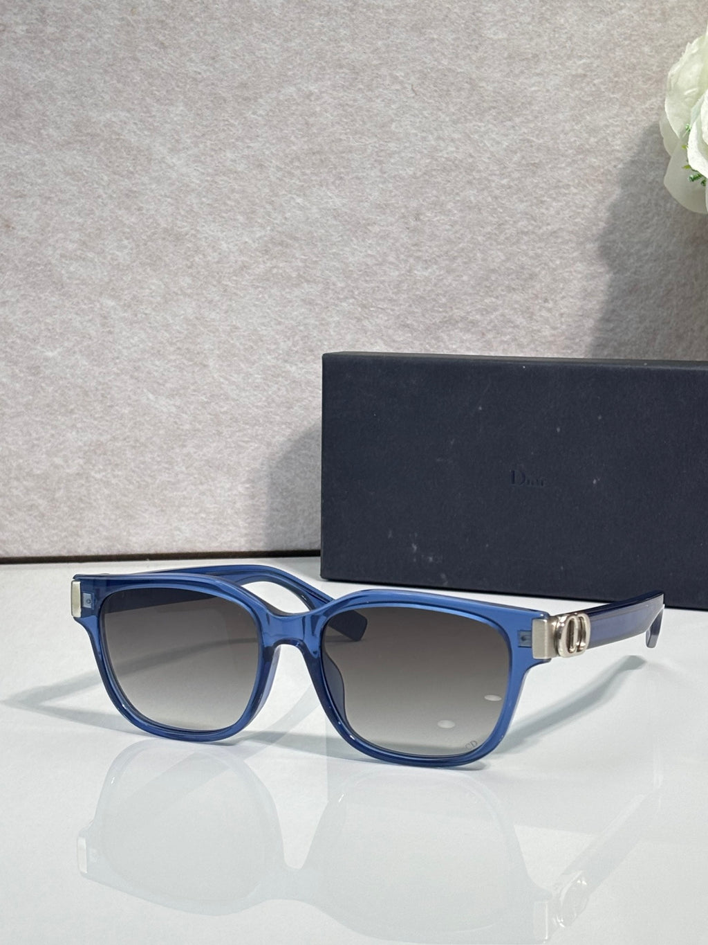 Dior sunglasses with blue frames, light tinted lenses, and gold logo hinge detail