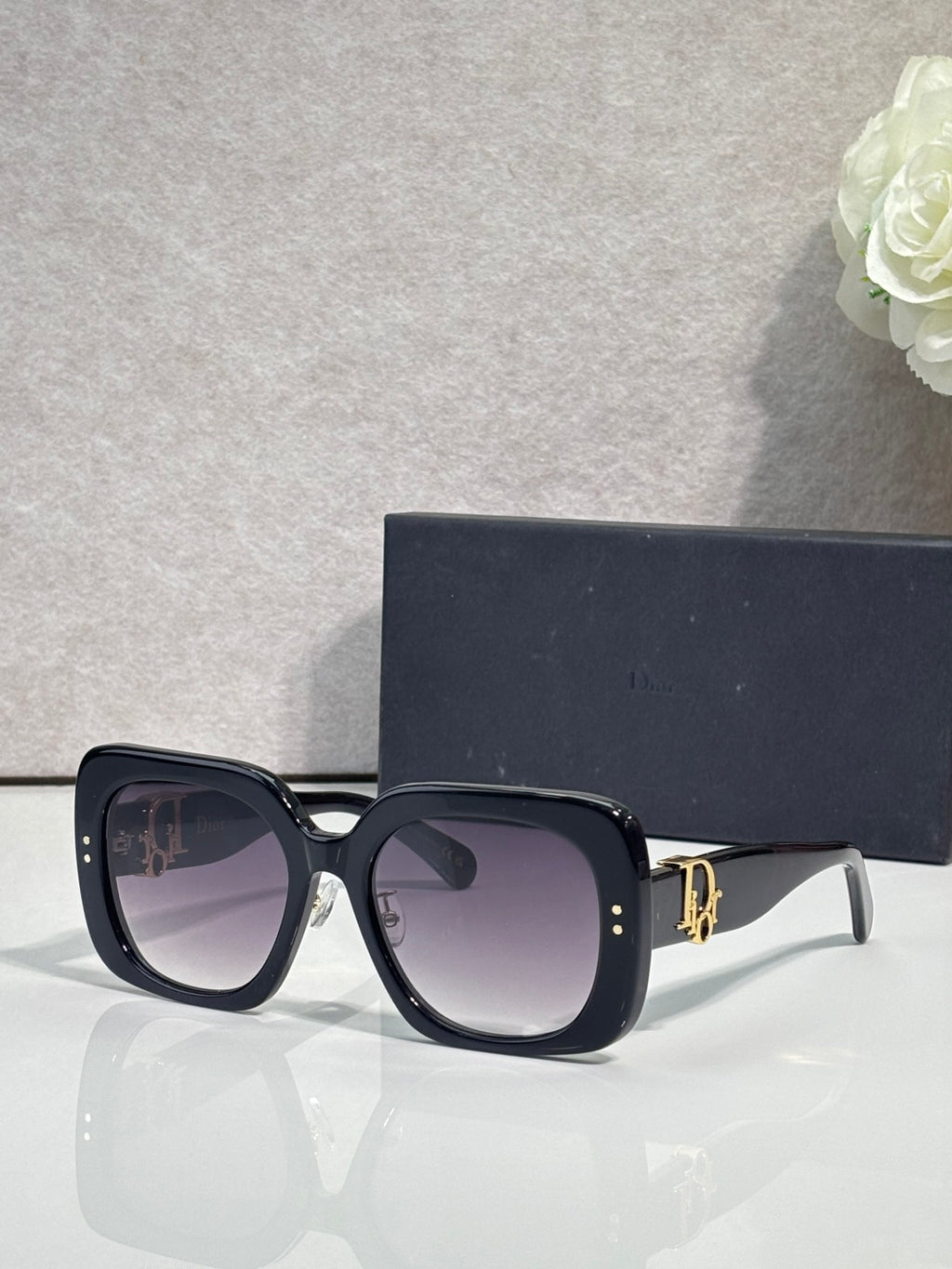 Black oversized square sunglasses with dark lenses and gold hinge detail
