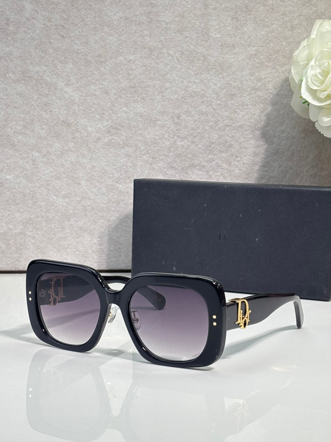 Black oversized square sunglasses with dark lenses and gold hinge detail