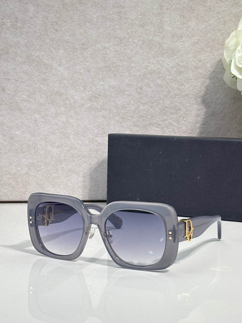 Slate blue square sunglasses with blue-tinted lenses and gold logo hinge