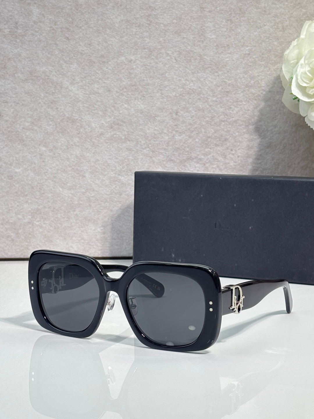 Black square sunglasses with dark lenses and gold logo hinge