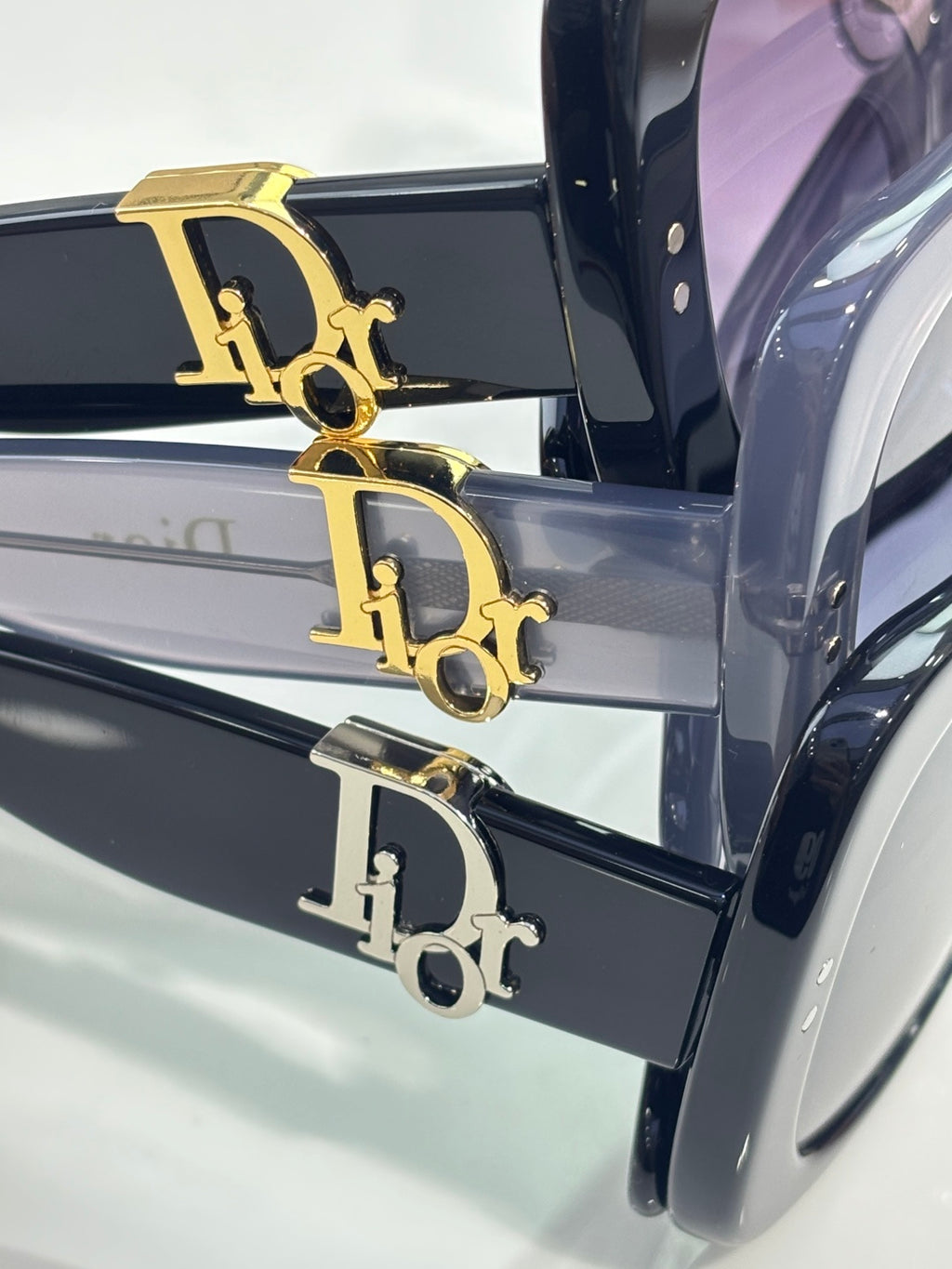 Close-up of black sunglasses with gold 'D' logo on the temple