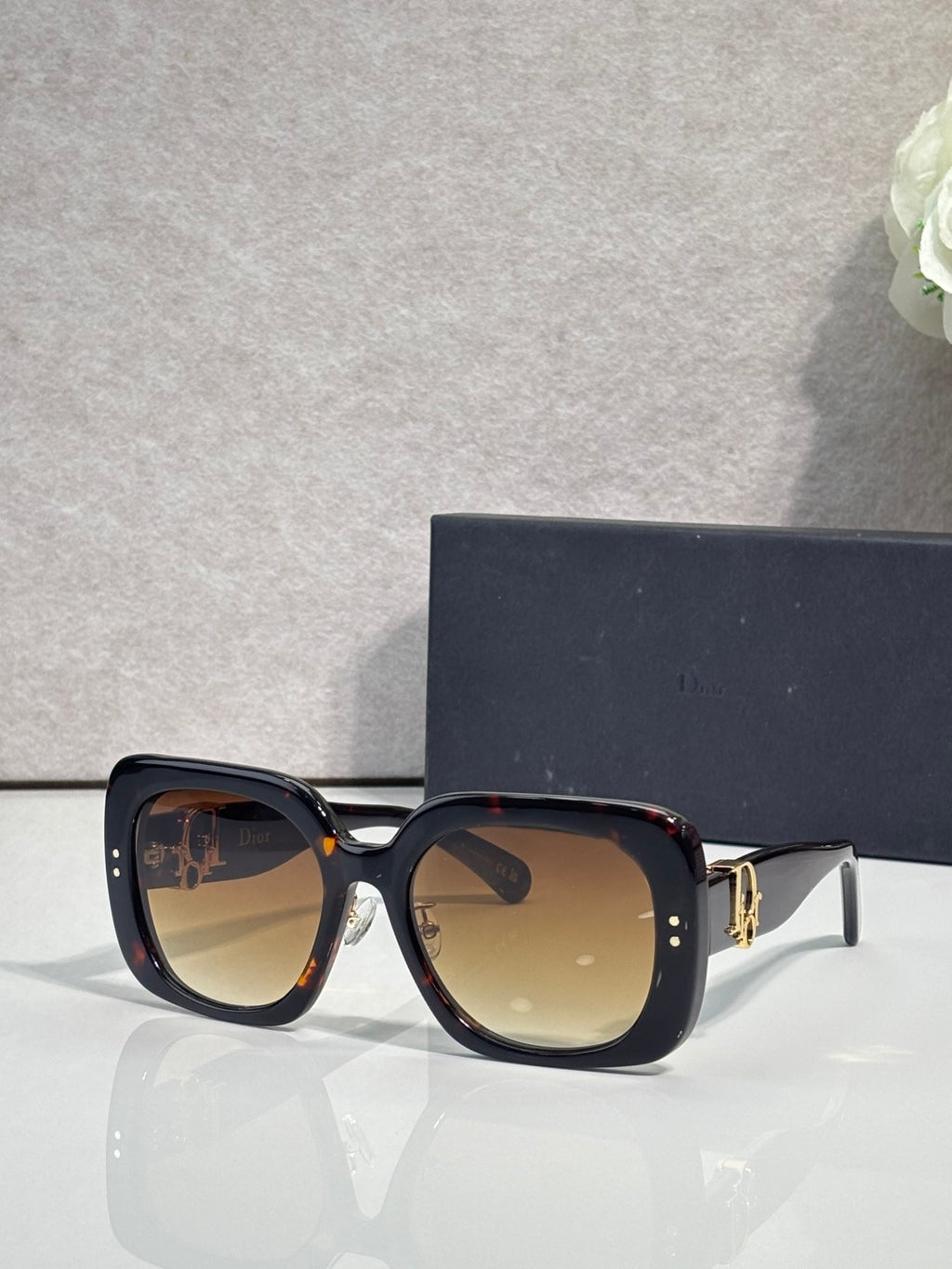 Black square sunglasses with amber-tinted lenses and gold hinge detail