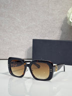 Black square sunglasses with amber-tinted lenses and gold hinge detail